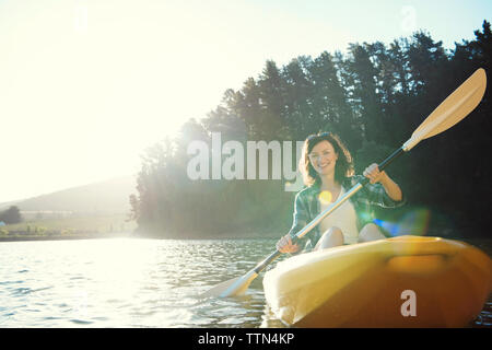 Portrait von Frau Kajakfahren auf dem See gegen Himmel während der sonnigen Tag Stockfoto