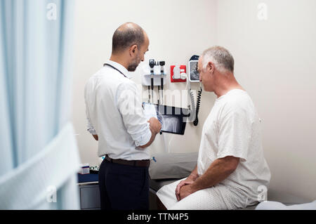 Arzt zeigt x-ray Berichte in Tablet Computer mit Patienten im Krankenhaus Stockfoto