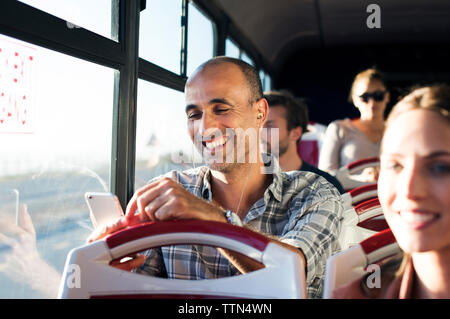 Glücklicher Mann mit Handy während der Fahrt im Reisebus Stockfoto