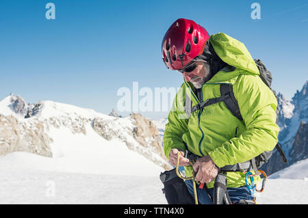 Männliche Wanderer stehen auf schneebedeckten Berg gegen den klaren blauen Himmel Stockfoto