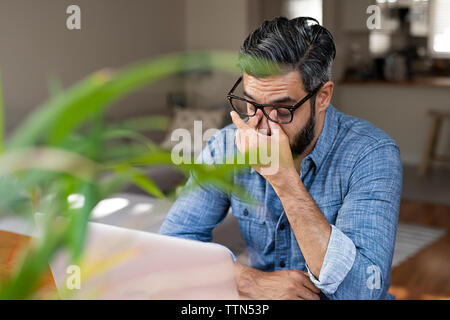 Hohe Betrachtungswinkel und der betonten Geschäftsmann mit Laptop zu Hause sitzen Stockfoto