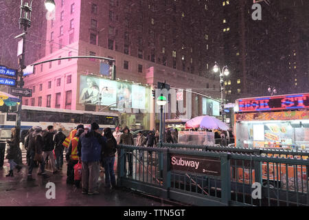 Pendler stehen außerhalb einer New Yorker U-Bahn Station in New York City während eines Schneesturms an der 7th Avenue in New York City, New York, USA Stockfoto