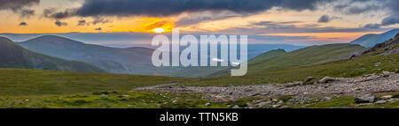 Panoramablick auf die Landschaft und Moody Himmel bei Sonnenuntergang über einen malerischen Berg Tal in Snowdonia, UK. Majestic View von Walking Route auf Snowdon Peak. Stockfoto