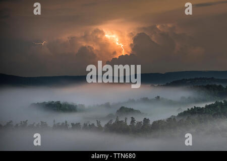 Blitz Wolken über Wald und Berg bei Nacht Stockfoto