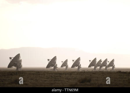 Satellitenschüssel auf Feld gegen Himmel während nebligen Wetter Stockfoto