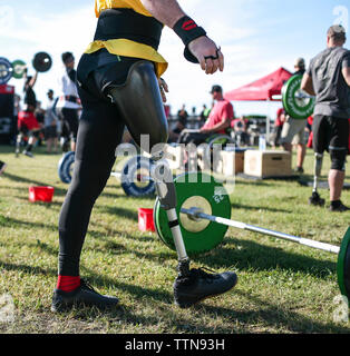 Niedrige Abschnitt der männlichen adaptive Athlet durch Kreuzheben auf der Wiese im Park Stockfoto