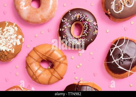 Ansicht der verschiedenen Donuts mit Konfetti auf rosa Hintergrund angeordnet Stockfoto