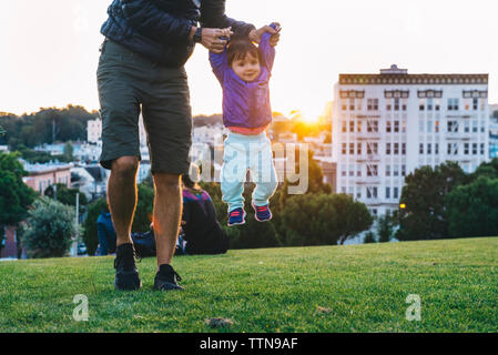 Untere Partie der Vater anheben niedlichen Tochter beim Spielen im Park Stockfoto