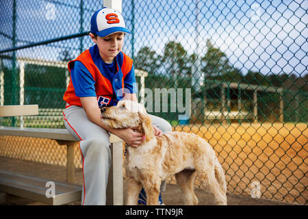 Baseballspieler streicheln Hund auf dem Feld Stockfoto