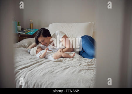 Glückliche Mutter mit Sohn, während am Bett zu Hause liegen Stockfoto