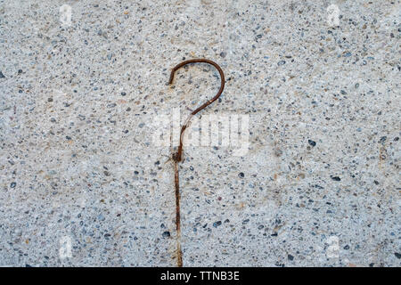 Fragezeichen, konzeptionelle Bild. Full Frame Bild von einer konkreten Oberfläche mit einem gebogenen, hervorstehende Stange aus Stahl. Weißer Hintergrund, kopieren. Stockfoto