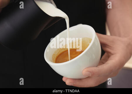 Mann Zeichnung auf Kaffee mit aufgeschäumter Milch Stockfoto