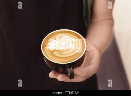 Mann mit Tasse Kaffee mit Latte Art Stockfoto