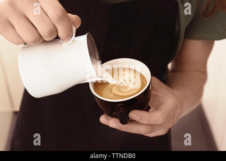 Mann Zeichnung auf Kaffee mit aufgeschäumter Milch Stockfoto