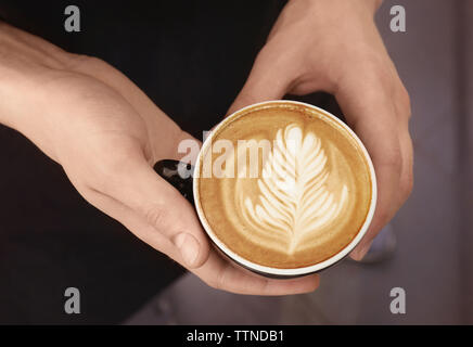 Mann mit Tasse Kaffee mit Latte Art Stockfoto