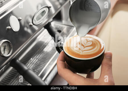 Mann Zeichnung auf Kaffee mit aufgeschäumter Milch Stockfoto
