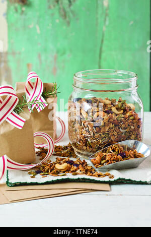 Nahaufnahme von Granola in Glas auf Holztisch gegen Wand zu Hause Stockfoto