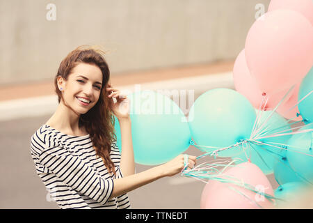 Porträt der schönen jungen Frau mit bunten Luftballons Stockfoto