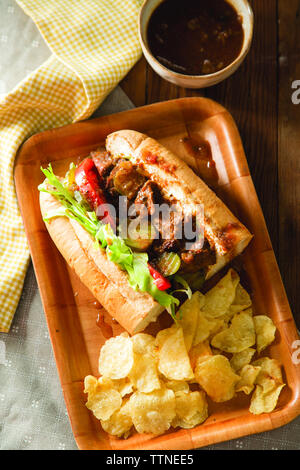 Blick von oben auf Po' Boy Sandwich mit Kartoffelchips im Tablett auf dem Tisch Stockfoto