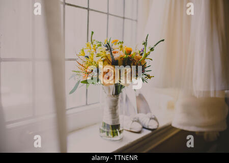 Blumenvase und Schuhe auf der Fensterbank von Wedding Dress Stockfoto