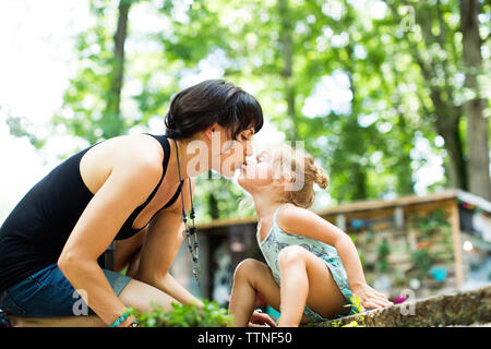 Liebevolle Tochter Mutter Küssen auf den Mund, während im Hinterhof sitzen Stockfoto