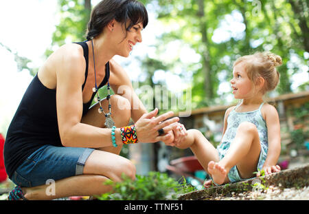 Mutter mit Tochter, während ihr Bein Holding im Hinterhof Stockfoto