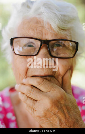 Close-up von nachdenklich ältere Frau mit der Hand am Kinn Brillen tragen Stockfoto
