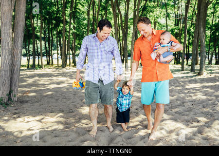 Homosexuelle coupé Wandern mit Kindern am Strand. Stockfoto