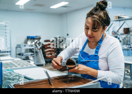 Weibliche baker Füllung Schokolade im Schuh geformte Behälter im Werk Stockfoto