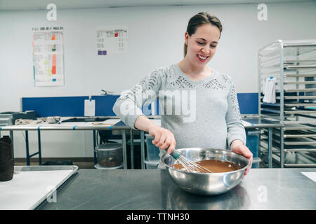 Lächelnd Küchenchef mischen Schokolade in der Schüssel im Werk Stockfoto