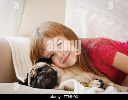 Adorable kleinen Mädchen und niedliche Mops auf Couch Stockfoto