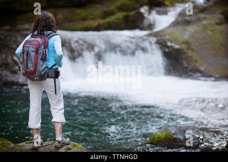 Junge Frau, die am Rande der Stream Stockfoto