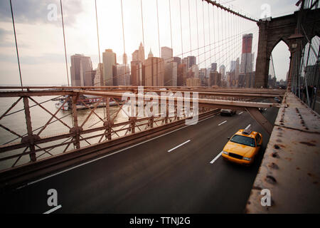 Gelbe Taxis und Autos auf der Brooklyn Bridge mit Blick auf die Stadt Stockfoto