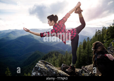 Frau Stehen auf einem Bein an der Klippe Stockfoto