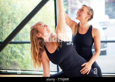 Ausbilder Unterstützung der Frau in Yoga Haltung im Studio Stockfoto