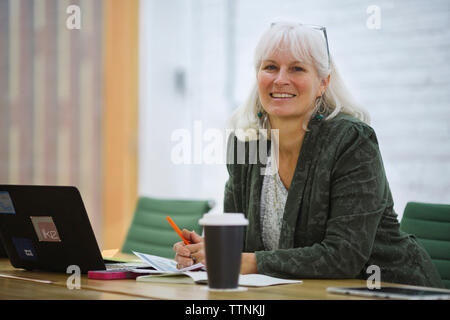 Portrait von lächelnden Geschäftsfrau mit Laptop sitzen im Board Room im Büro Stockfoto