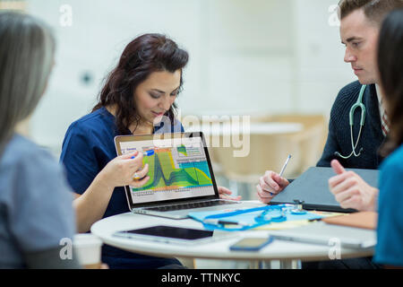 Weibliche Arzt die Aufklärung der Mitarbeiter über Laptop in der Sitzung an den medizinischen Zimmer Stockfoto