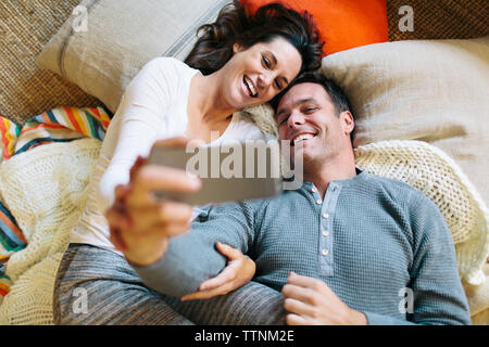 Draufsicht des Paares unter selfie beim Liegen auf dem Teppich zu Hause Stockfoto