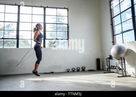 Seitenansicht des weiblichen Athleten überspringen mit Seilspringen in der Turnhalle Stockfoto