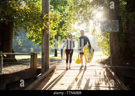 Paar mit paddleboards Wandern am Boardwalk Stockfoto