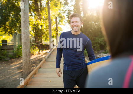 Portrait von Mann paddleboard beim Stehen mit Frau am Boardwalk Stockfoto