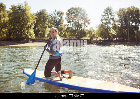 Porträt der lächelnde Frau paddleboarding auf dem Fluss Stockfoto