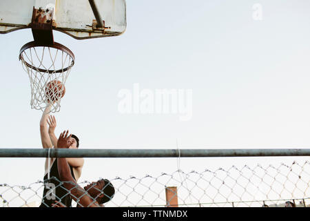 Niedrigen Winkel Ansicht von Freunden Basketball zu spielen, gegen klaren Himmel Stockfoto