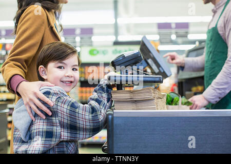 Portrait der Junge mit der Mutter steht im Supermarkt Stockfoto
