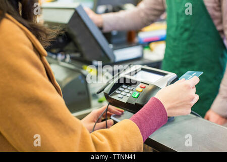 Mittelteil der Frau Zahlung Rechnung mit Kreditkarte im Supermarkt Stockfoto