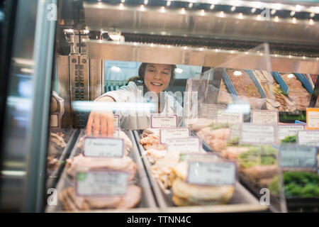 Arbeitnehmerinnen, die die Nahrung in Vitrine im Supermarkt Stockfoto