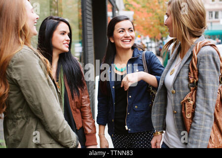 Gerne weibliche Freunde sprechen, während sie von Restaurant stehend Stockfoto