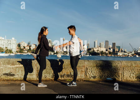 Junges Paar Hände halten, während sich die Beine an der Promenade gegen Stadtbild Stockfoto