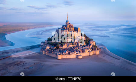 Luftaufnahme von Mont Saint-Michel von Fluss gegen Himmel bei Sonnenuntergang Stockfoto