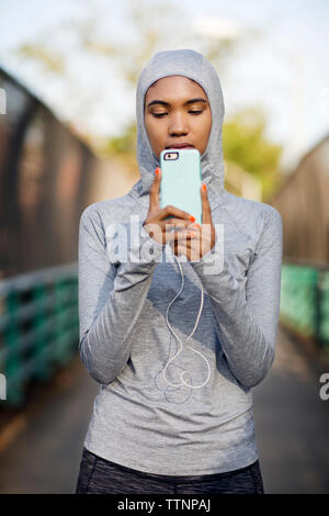 Frau T-Shirt tragen, während Sie smart phone auf Fußweg Stockfoto